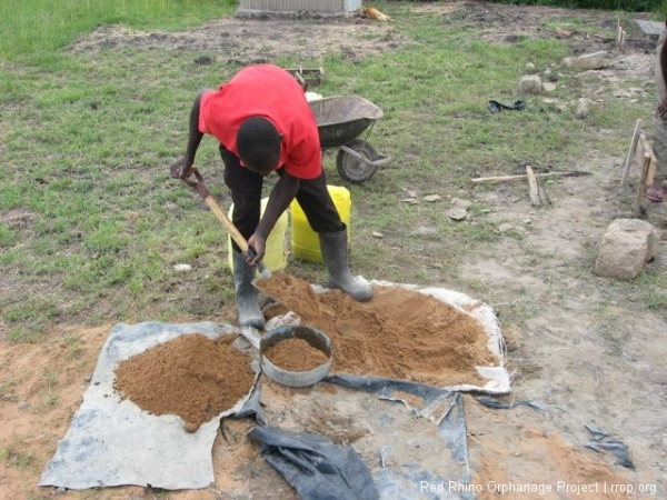 Gilbert mixing the concrete in our hi-tech facility. The proportions for the foundations are: 1-cement to 3-sand to   6-ballast (small stones). For the mortar between the stones it is: 1 cement to 4 sand.