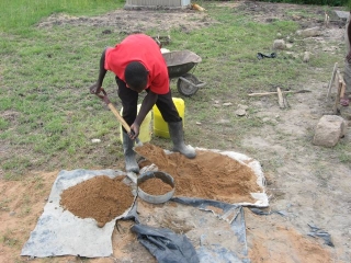 Gilbert mixing the concrete in our hi-tech facility. The proportions for the foundations are: 1-cement to 3-sand to   6-ballast (small stones). For the mortar between the stones it is: 1 cement to 4 sand.