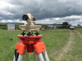 Then we set up this beauty, a borrowed sight level, and took some preliminary ground readings to determine the degree of slope in our exquisite rectangle. That\'s Gilbert in the background holding the 8\' measuring rod.