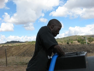 Peter wrassli\' with the blue snake...pumping water from our tank to the one in the back of the pick up. Our mobile watering unit for soil compaction.