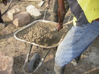 Then wheelbarrowed concrete to each one,          