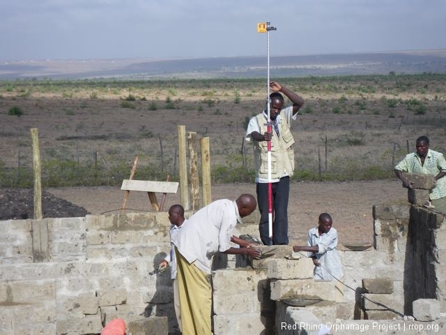 If you click and look closely, you can see the red laser beam caught in Gilbert\'s surveyor\'s measuring pole. We use these to set the level of each course of stones.